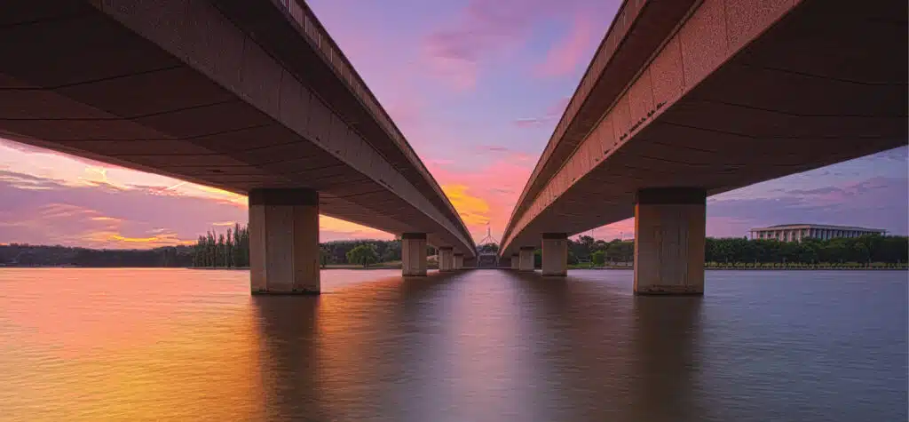 Freeway bridge over water at sunset.